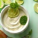 Topeng muka dengan tekstur berkrim dan alat pengaplikasi, dikelilingi oleh hirisan limau dan daun pudina.